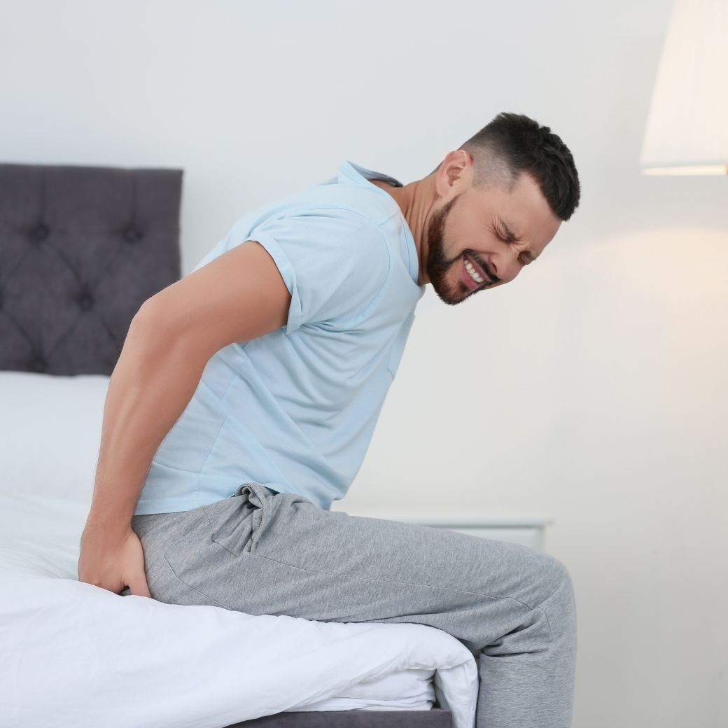 A man feeling the pain of piles while sitting in his bed